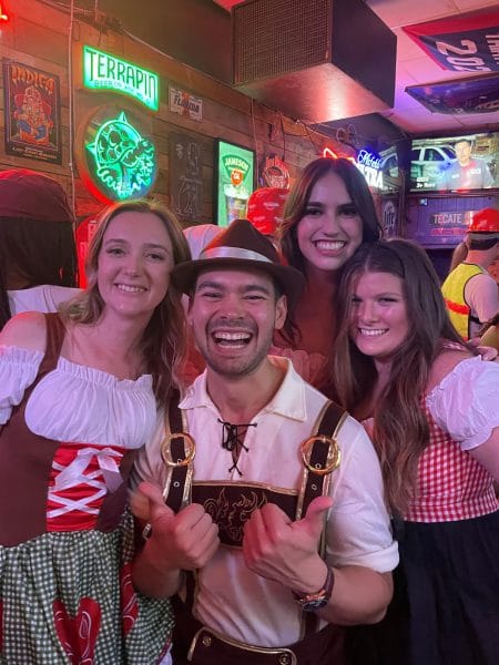 Benedikt Stocker and three female friends dressed in traditional German outfits inside of a pub.