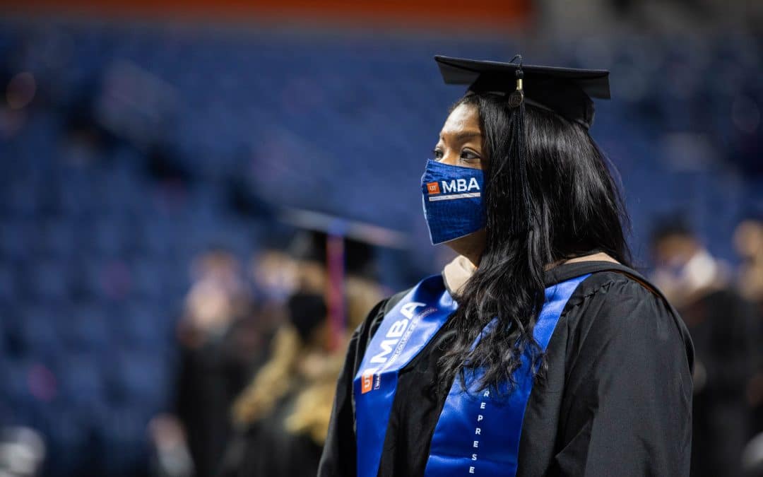 Young Black woman wearing commencement regalia stands during a graduation ceremony.
