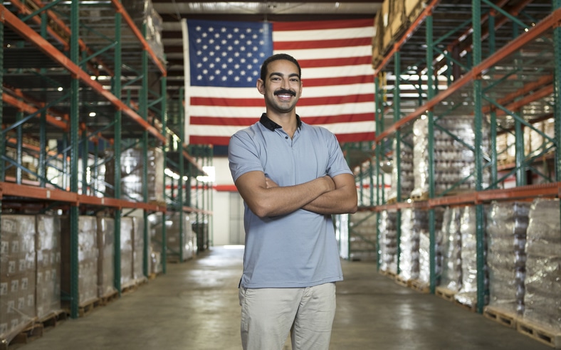 David Habib stands in a warehouse with an American flag behind him.