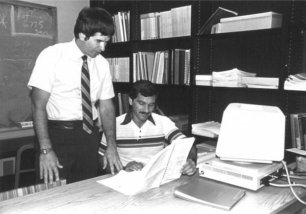 Wayne Archer looks at a document with a student