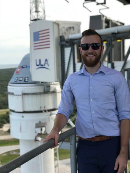 Nathaniel Keyek-Franssen stands at the top of a launchpad where the Boeing Starliner sits atop a rocket at Kennedy Space Center.