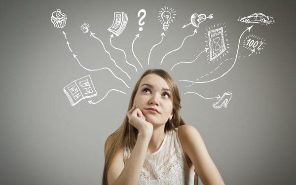 Young woman looking up while thinking about various things - books, money, diploma, ideas and love.