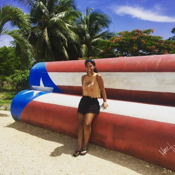 Laurie Rodriguez poses for a photo in front of a large Puerto Rican flag