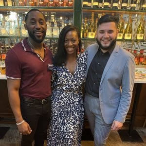 Two men and a woman pose for a photo at a networking event
