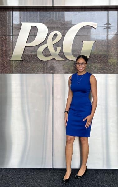 Taylor Smellie poses for a photo with a large P&G logo sign