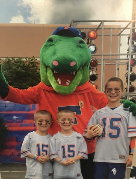 Exum boys wearing football jerseys with the #15 on them and the Gator mascot, Albert, standing with them