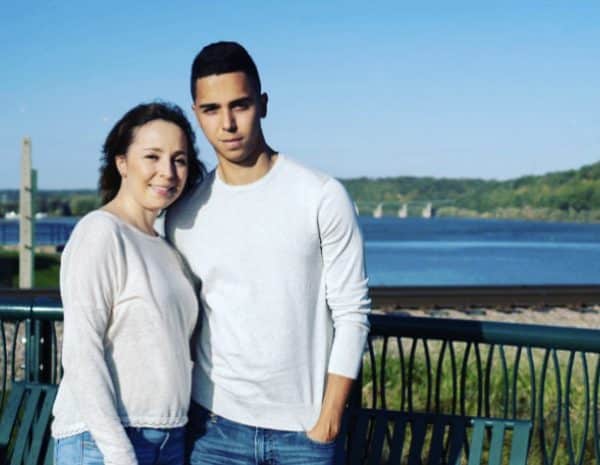 Jorge Ramirez and his mom pose for a photo in front of a large body of water