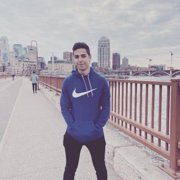 Jorge Ramirez stands on a sidewalk with a city skyline in the background