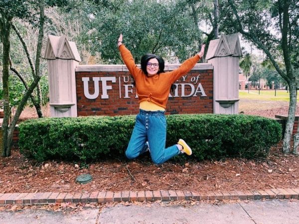 Martha Coro jumps in front of a University of Florida sign.
