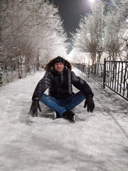 Igor Savin sits in the snow, bundled in a winter coat.