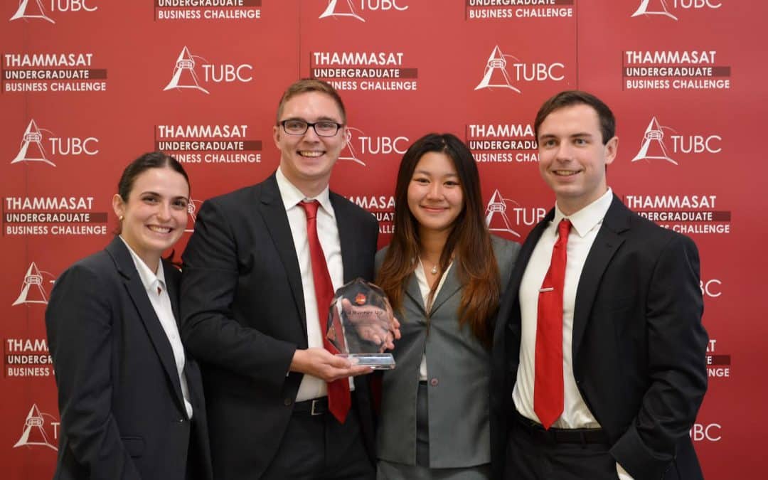 Heavener students Luke Carter (BSBA ’23), Michael McClesky (BSBA ’23), Jordana Schube (BSBA ’22, MS-Marketing ’23) and Beata Chen (BSBA ’23, MSF ’24) pose for a photo in front of a red step-and-repeat with their trophy from the Thammasat Undergraduate Business Competition.