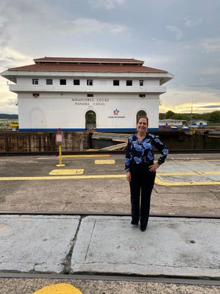 Lynn Isaak stands in front of the Panama Canal.