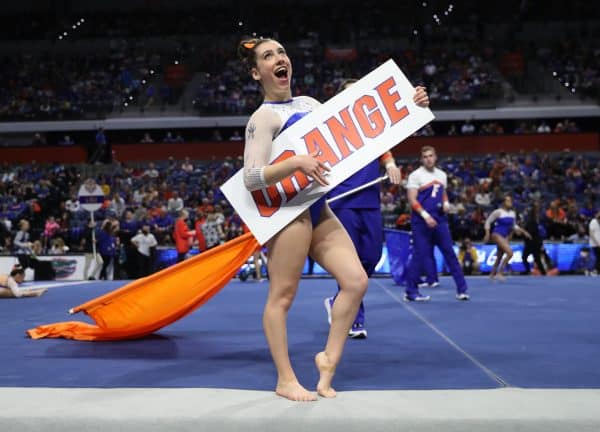 Leah Clapper poses with a sign at a gymnastics competition.