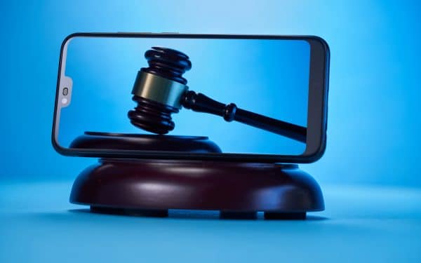 Gavel hammer with smartphone on blue background. Justice and law concept.