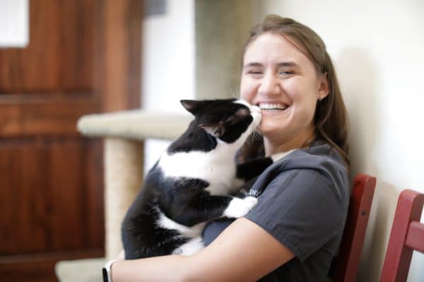 Grace White is holding a black and white cat.
