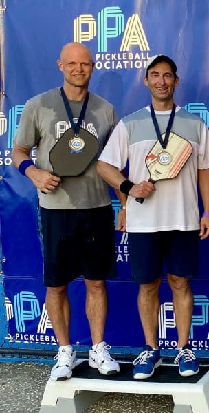 Brian Levine and Danny Wuerffel pose with gold medals and Pickleball paddles.