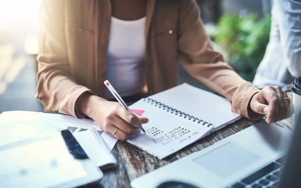 Woman writes a list in front of a computer