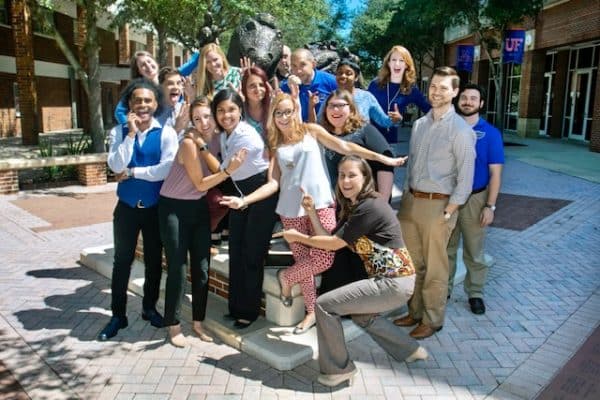 UF students and alumni pose in front of a gator statue.