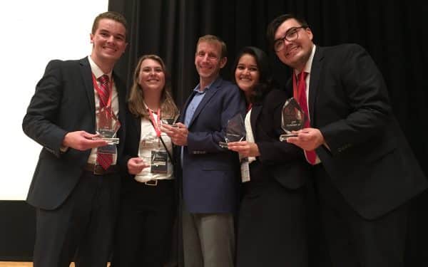 Dr. John Banko with students, holding awards.