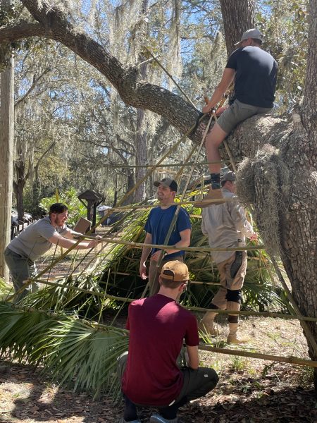 Students building a shelter out of palm leaves.