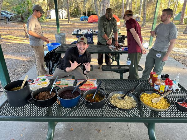 A student poses behind a table of food.