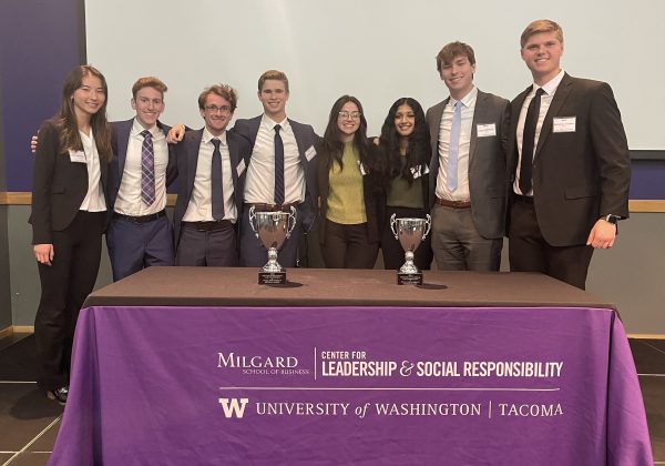 Students pose with trophies placed on a purple tablecloth.