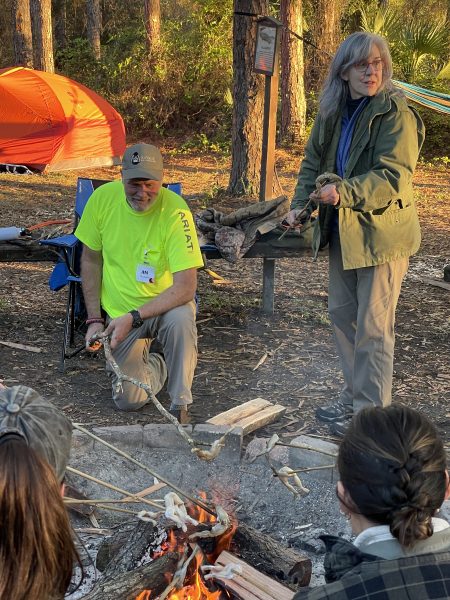 Judy and her husband roast frog legs over a campfire.