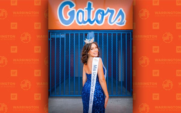 Zoe Larson stands under a Gators sign wearing a crown and a Miss University of Florida ribbon.