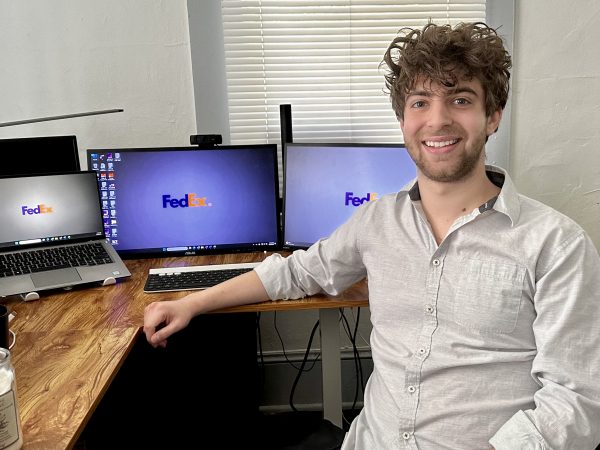 Taylor Anderson sits at a computer with FedEx logos on the monitors.