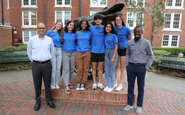 Saby Mitra and Jeff Danso with six student leaders stand in front of a large bronze Gator statue