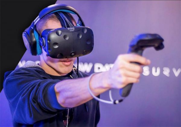 A man uses a virtual reality headset and handheld gaming controller.