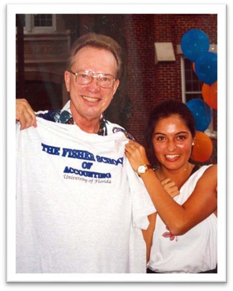 Fred Fisher holds a t-shirt that reads Fisher School of Accounting with a student