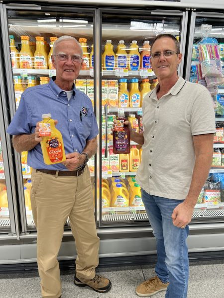 Matt McLean and his father stand in the refrigerated section of a grocery store holding bottles of Uncle Matt's Organic juice.