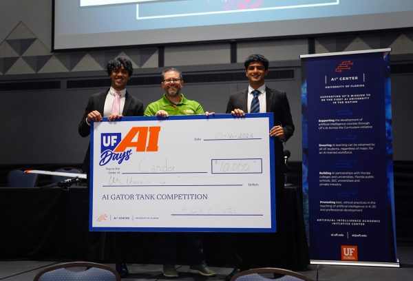 Two students a faculty member hold a $10,000 prize check.
