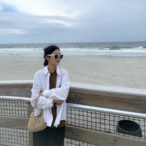 Yiwei Jin wears sunglasses on a beach.
