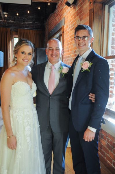 Sean Limon poses with a bride and groom.