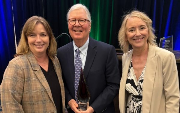 Gary McGill holding an award with two representatives from the American Accounting Association