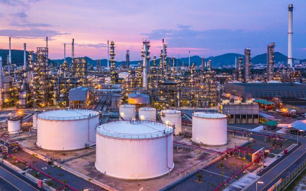 Aerial top view oil and gas chemical tank with oil refinery plant background at twilight.