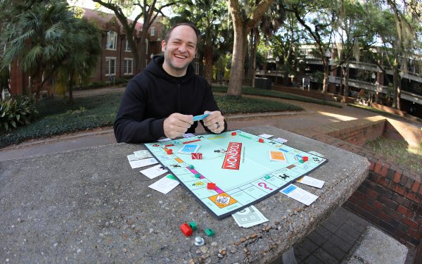 Paul Madsen sits behind a Monopoly board.