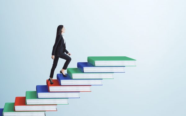 Businesswoman climbing book pile ladder. Sky background. Education and career concept