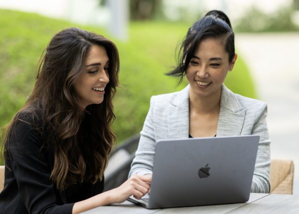 Nicole Rechtszaid and Jenny Woo look at a laptop together.