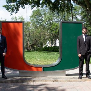 Students pose next to statue at University of Miami.