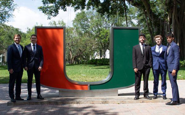 Students pose next to statue at University of Miami.