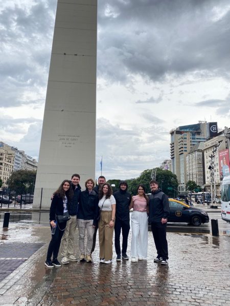 A group poses in front of a monument.