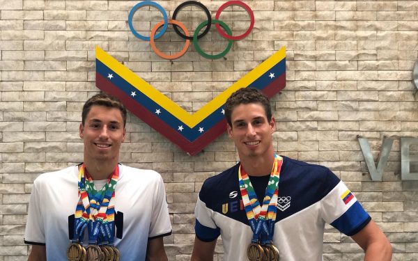 Alfonso Mestre and Alberto Mestre stand in front of the Olympic rings