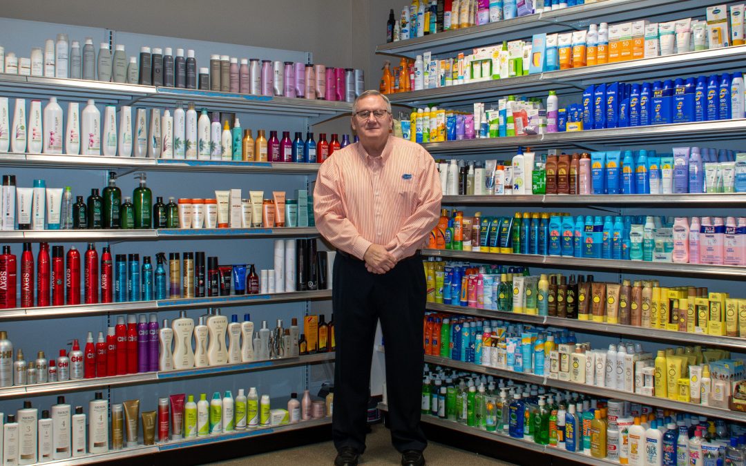 Chip Lane stands in front of hair and sun care products on a mock retail store shelf.