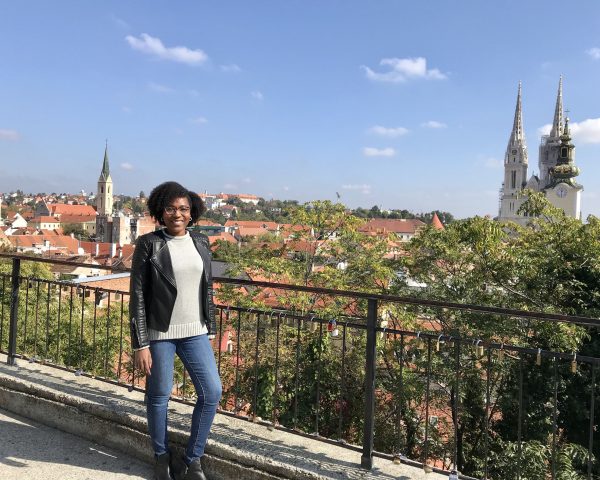 Lisa Thelwell poses for a photo in front of a cityscape in Europe.