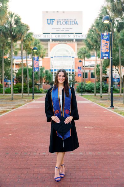 Chloe Grimme in graduate regalia with Ben Hill Griffin stadium and palm trees in the background.