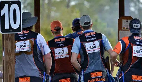 Steve Tufts with the UF shooting team. A photo from behind of a group of 5 men stand together wearing vests with competition bibs.