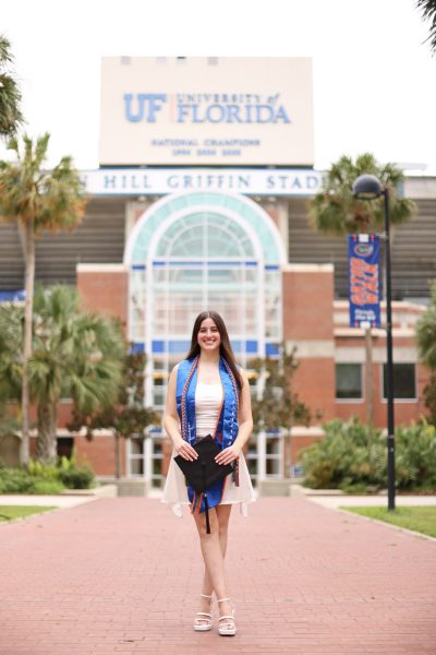 Melanie Jakubowicz poses in graduation regalia in front of the Ben Hill Griffin stadium.